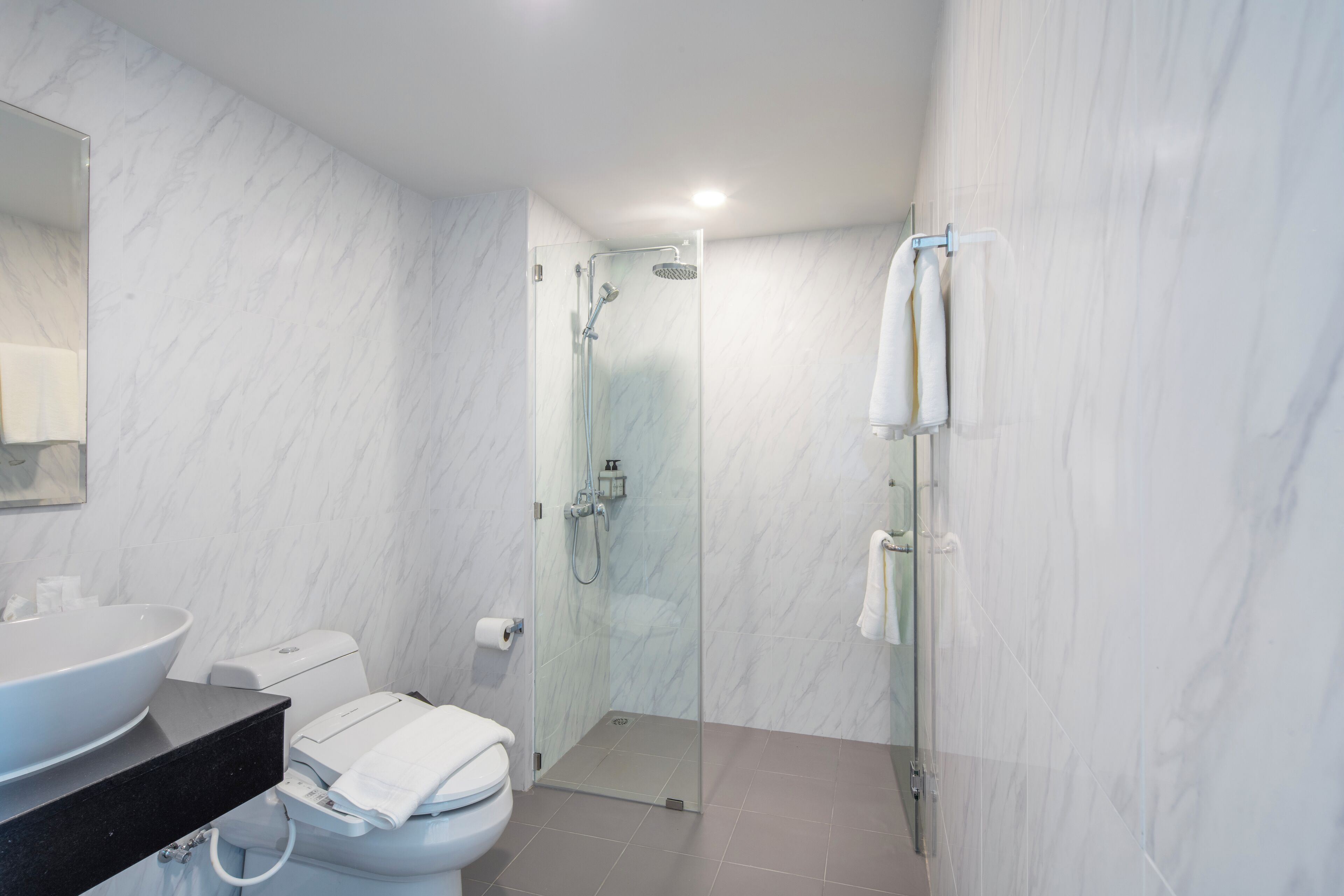 Ein modernes Badezimmer mit einer Duschkabine, einem weißen Waschbecken und einer Toilette.