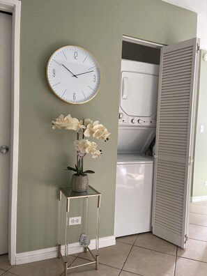 Relax in a serene space with a clock, vase, and laundry area nearby.