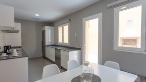 Een moderne keuken met witte kasten, een inbouwoven en een groot raam.