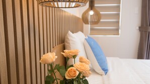 A bedroom with a wooden headboard, a bedside table with a vase of flowers, and a hanging light fixture. -  The View Hotel (Cam Lam)