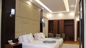 Een hotelkamer met twee bedden, een nachtkastje van hout, een bureau, een stoel en een kledingkast.