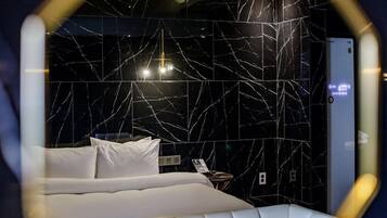 Ein modernes Hotelzimmer mit einer Wand aus schwarzem Marmor, einem weißen Bett und einem Nachttisch mit Telefon.