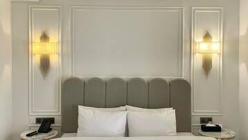 Habitación de hotel con una cama grande, dos mesitas de noche, un cabecero moderno e iluminación empotrada en la pared.