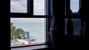 Vista attraverso una finestra sul mare e su un edificio con tetto rosso.