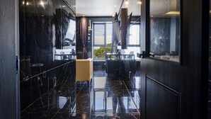 Una hall d'hotel moderna con pavimento in marmo, un'area salotto centrale e ampie finestre con vista sull'esterno.