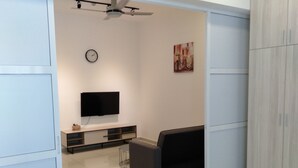 A modern living room with a flat-screen TV, a sofa, a coffee table, and a clock on the wall. - Summer Studio 2 - One South (Seri Kembangan)