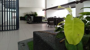 A modern indoor space with a seating area, a staircase, and a decorative plant. - Summer Studio 2 - One South (Seri Kembangan)