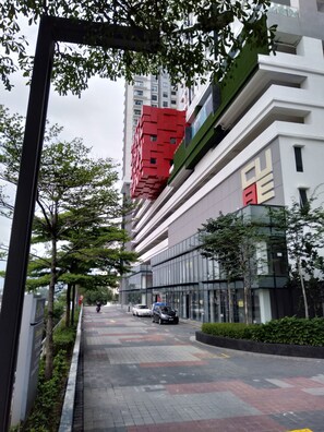 A modern building with a red and white facade, surrounded by trees and a paved walkway.