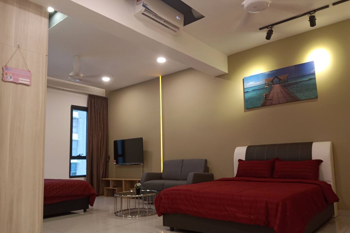 A modern hotel room with a large bed, a smaller bed, a sofa, a TV, and a painting on the wall.