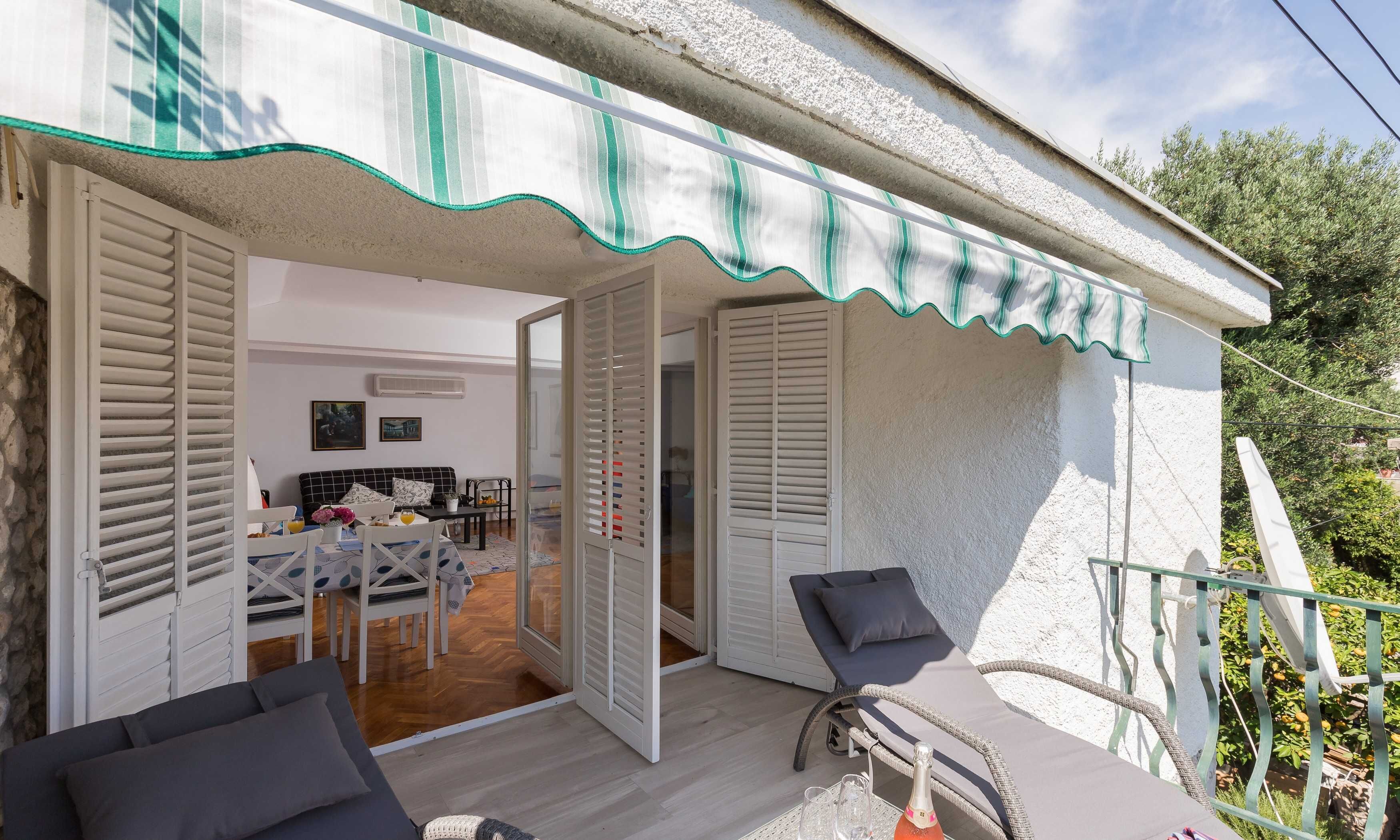 A covered outdoor seating area with a table and chairs, a bicycle, and a balcony with a railing.