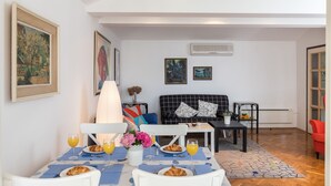 Un comedor con una mesa dispuesta para el desayuno, un sofá y una mesita auxiliar con una lámpara.