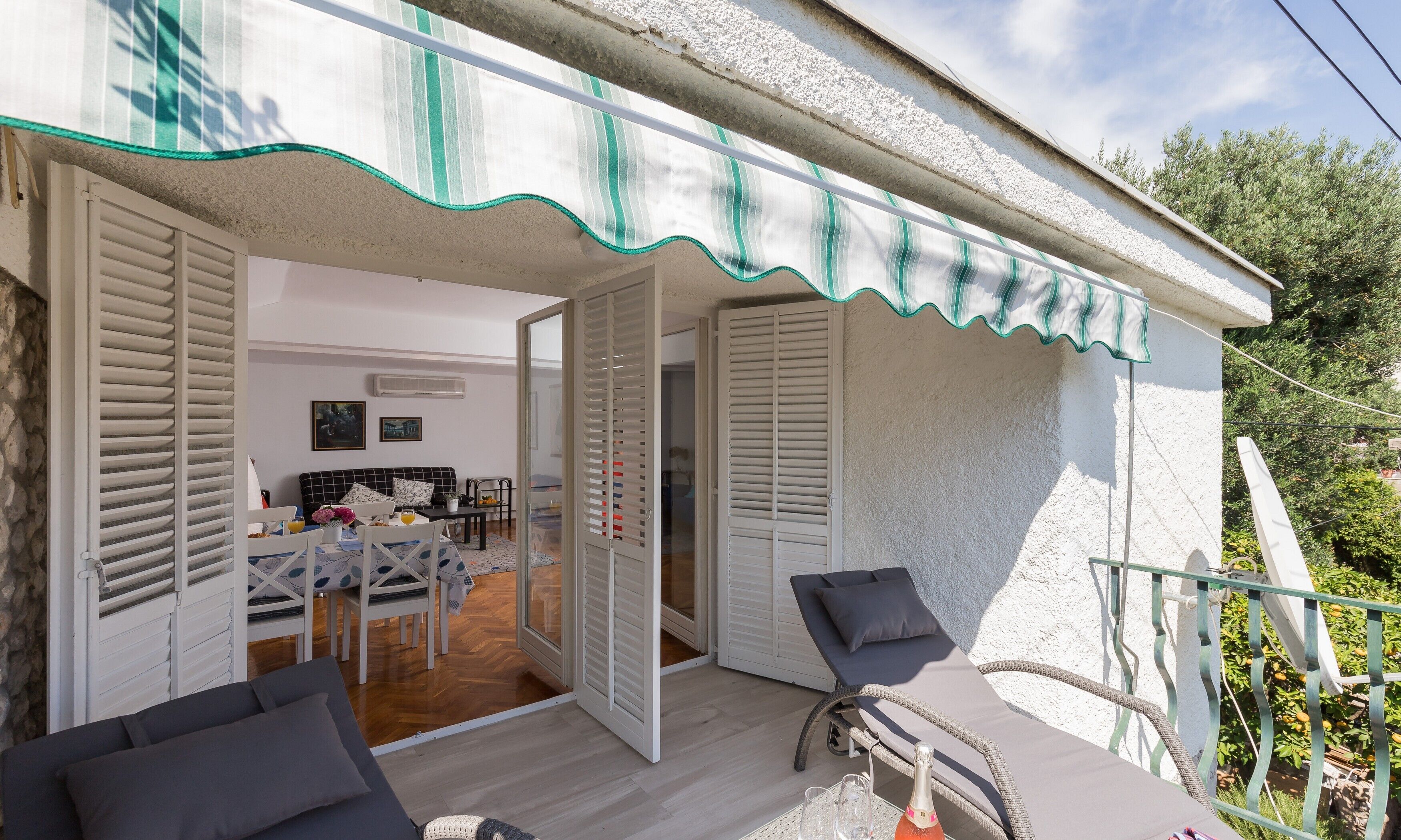 A cozy outdoor seating area with a table and chairs, a bicycle, and a balcony with a railing.