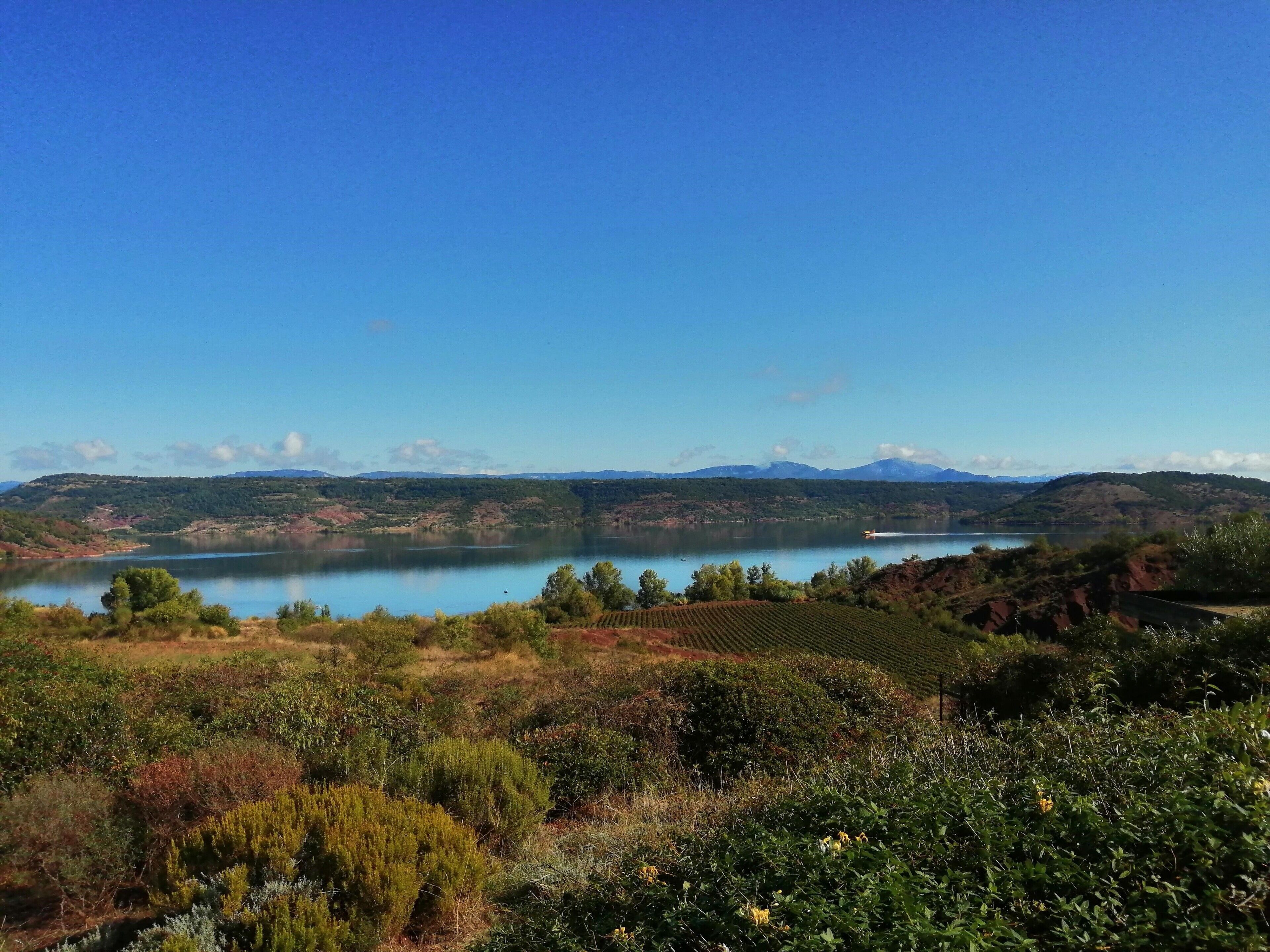 Una vista pintoresca de un lago rodeado de colinas y vegetación.