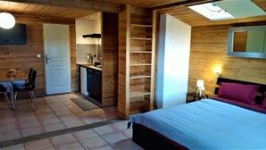 Un intérieur en bois comprenant un lit, un bureau et un coin cuisine.