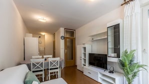 A modern living room with a sofa, TV, and a dining area with chairs and a table. - Apartment Gordana (Split)