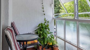 A small balcony with a table and chairs, potted plants, and a view of the outside. - Apartment Gordana (Split)