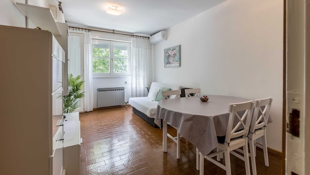 A cozy room with a dining table, white chairs, a sofa, and a window with curtains. - Apartment Gordana (Split)