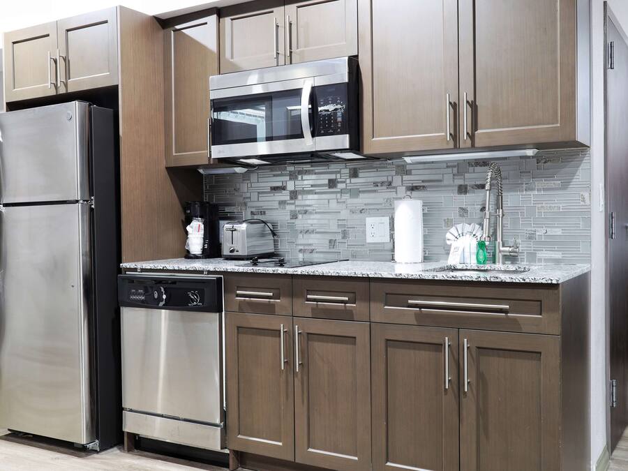 A modern kitchen with stainless steel appliances, wooden cabinets, and a tiled backsplash.