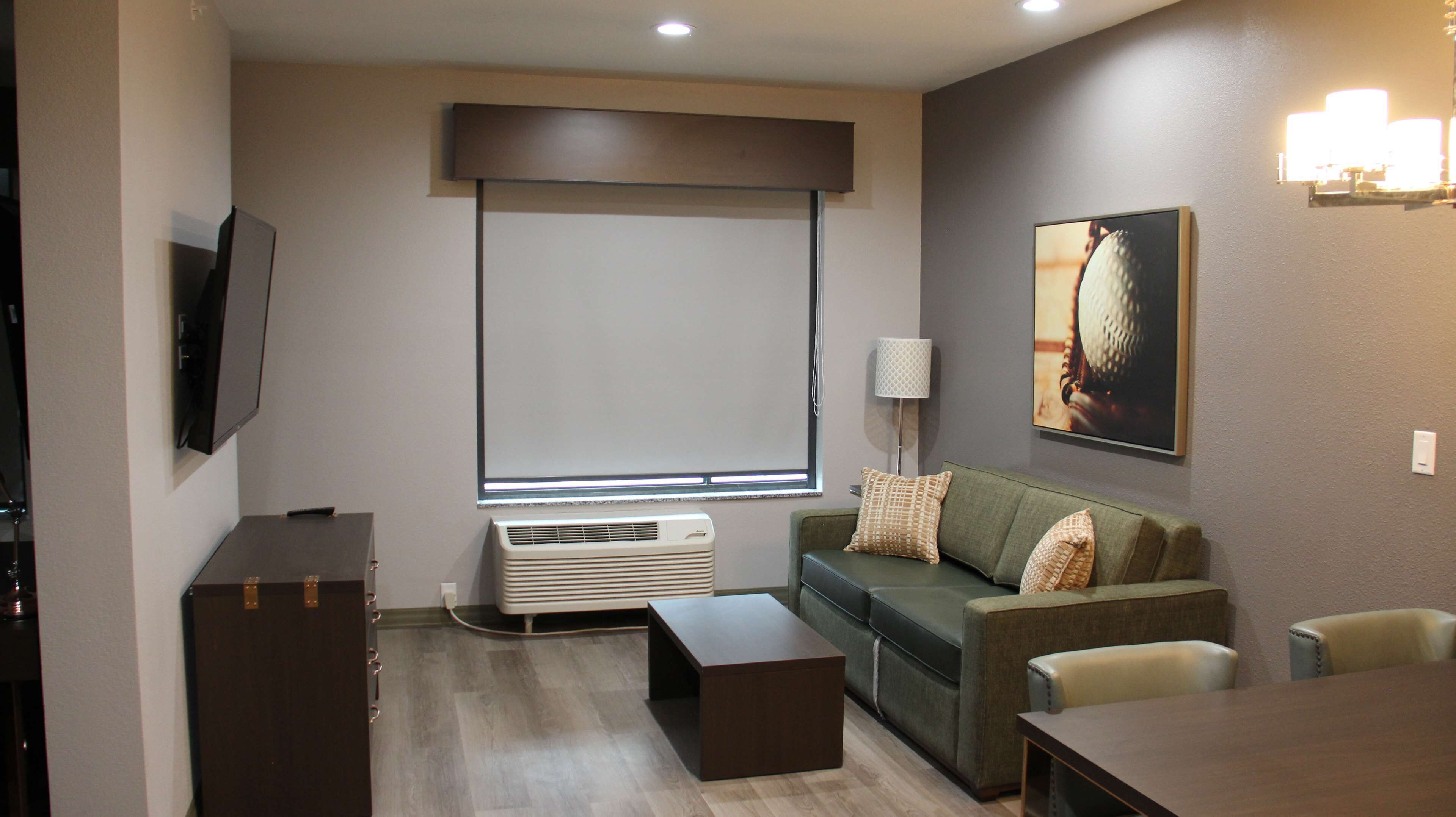 A modern living room with a sofa, a coffee table, a TV, and a wall-mounted air conditioner.