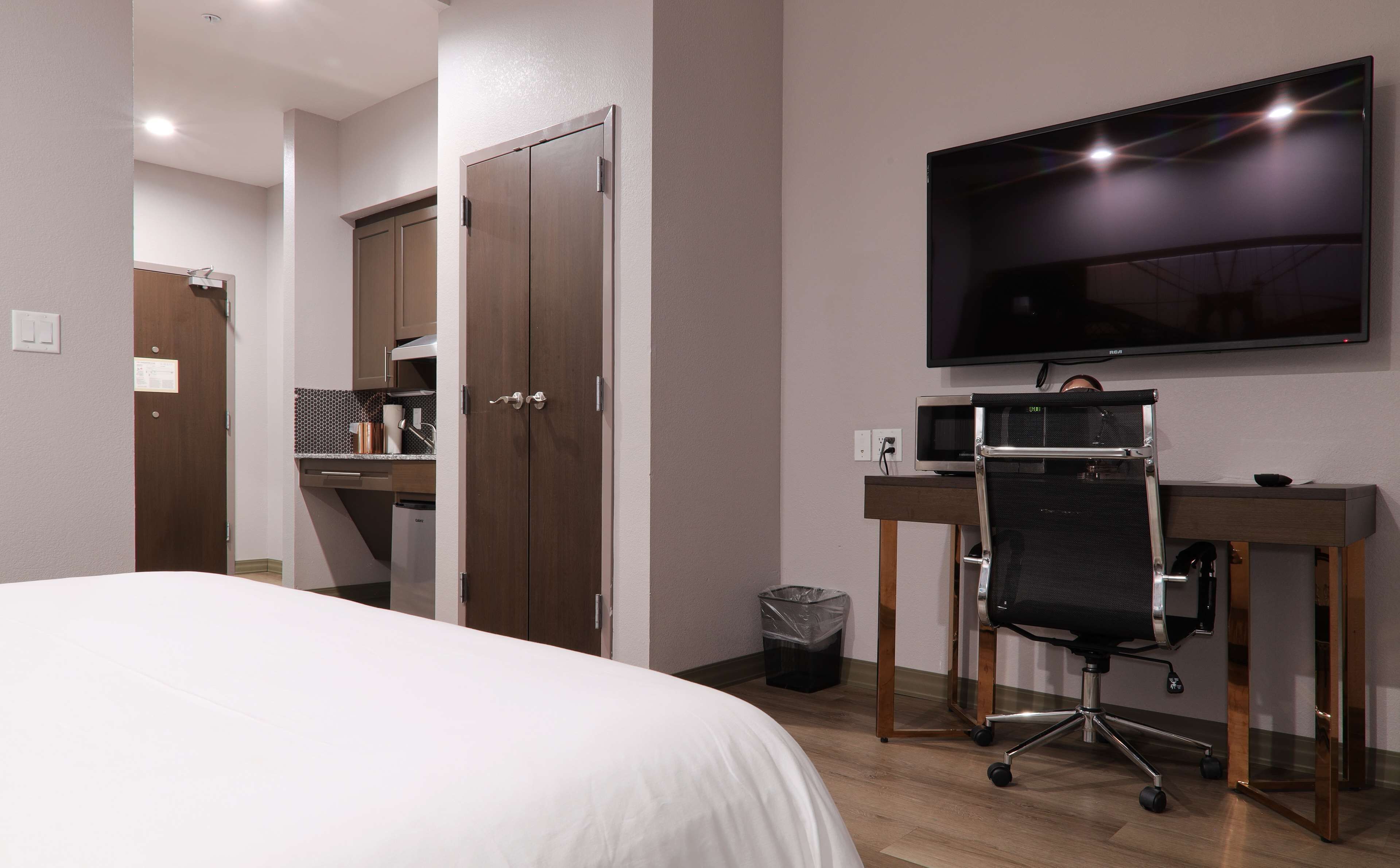 Une chambre d’hôtel comprenant un lit, un bureau avec une chaise, une télévision et une poubelle.