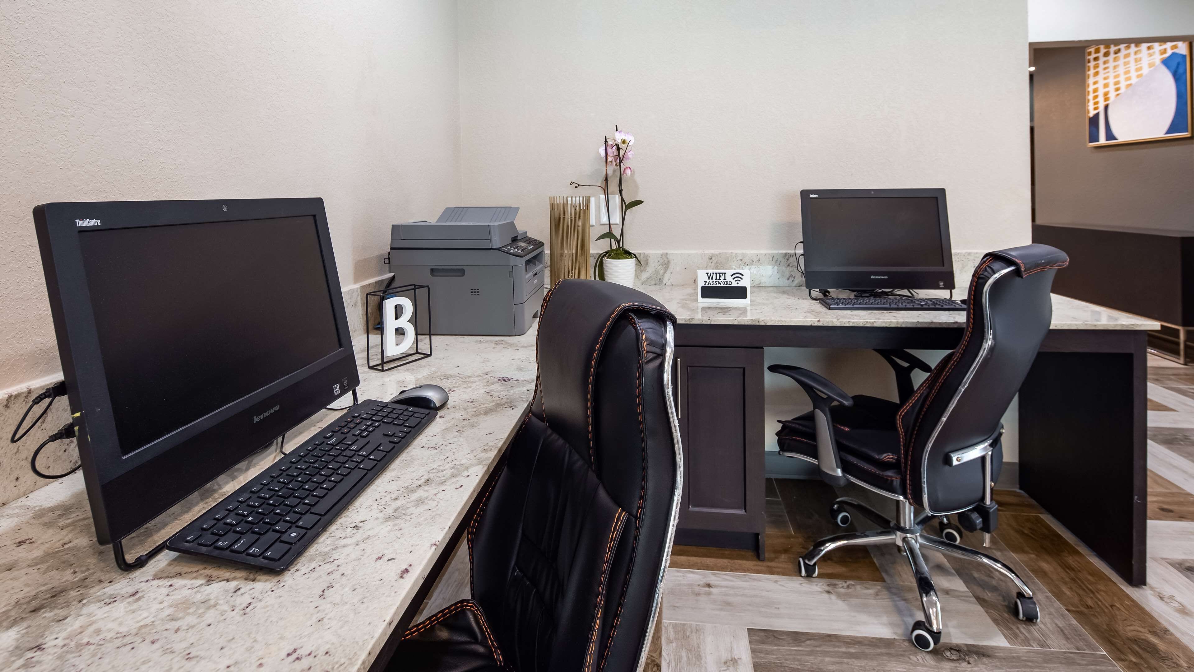 Un espacio de oficina moderno con dos monitores de computadora, un teclado, un ratón y una silla de oficina de cuero negro.