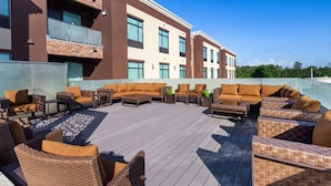 A rooftop patio with outdoor furniture, a view of a modern building, and a clear sky. - Hotel Manhattan, BW Signature Collection (New Caney)