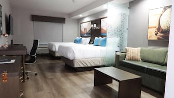 Una habitación de hotel moderna con dos camas, un escritorio, una silla, un sofá y una mesa de centro.
