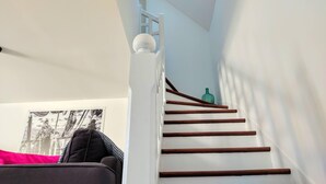Una escalera con balaustres blancos y peldaños de madera que conducen a un rellano.