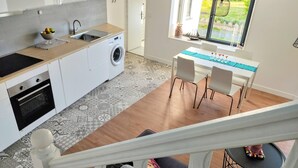 Una cocina moderna con lavadora, un lavamanos y una zona de comedor con mesa y sillas.