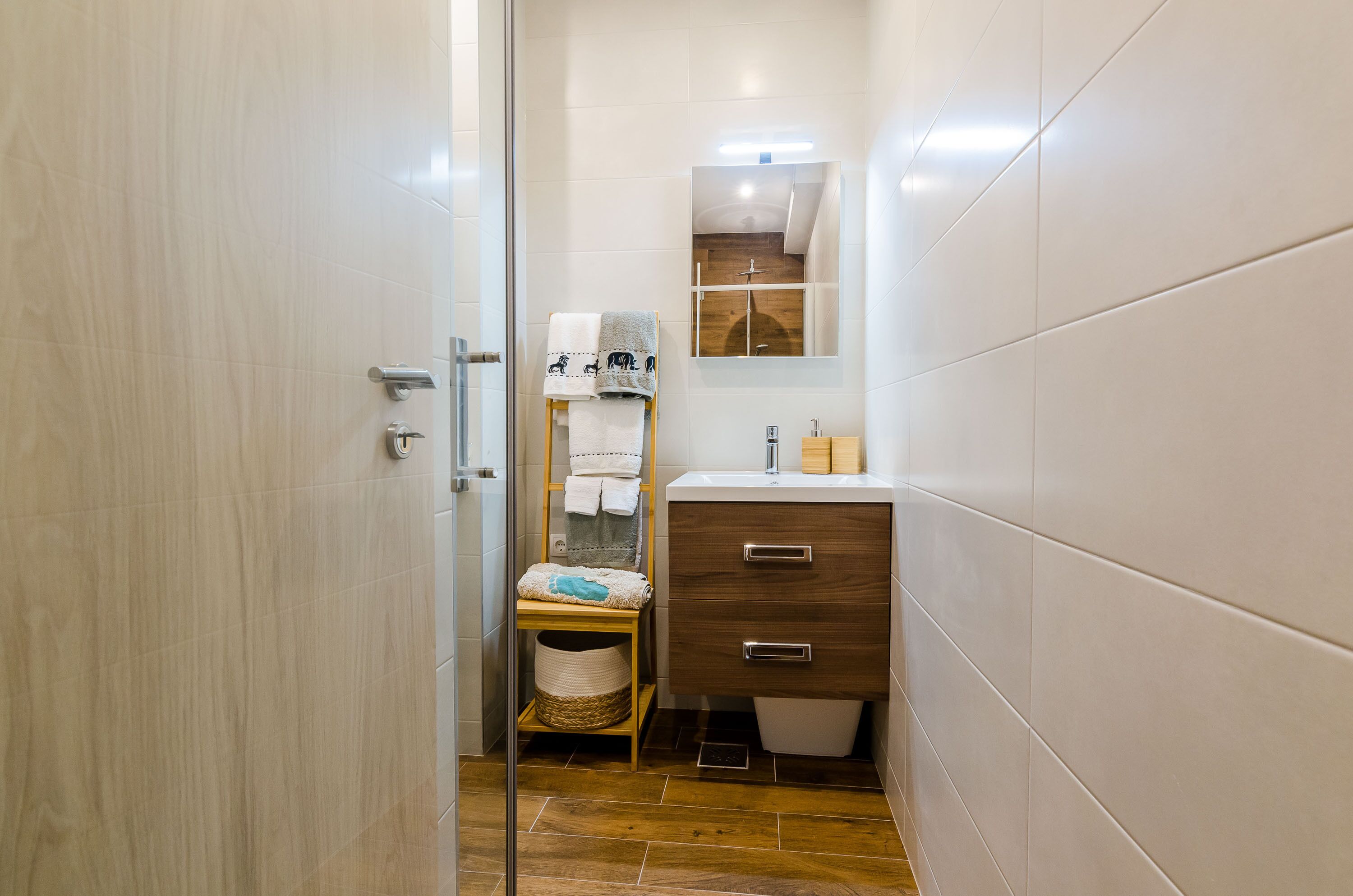 Une petite salle de bain avec un meuble-lavabo en bois, un porte-serviettes orné de serviettes à motifs et un miroir au-dessus du lavabo.