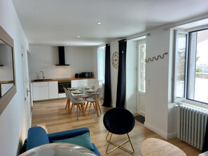Een modern appartement met een eethoek, keuken en een groot raam met gordijnen.