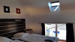 A hotel room with two beds, a skylight, a view of the outside, and a small table. - Gite in the heart of an artisan village - marsh views - near ocean (Sallertaine)