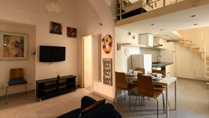 Un amplio salón con televisor de pantalla plana, una mesa de comedor con sillas, una cocina y una escalera que conduce a un nivel superior.