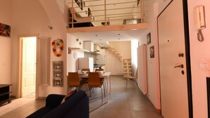 Un espacio habitable compacto con comedor, kitchenette y dormitorio en entrepiso.