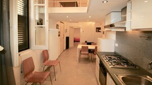 Una cocina moderna con estufa a gas, un lavamanos y una zona de comedor con sillas y mesa.