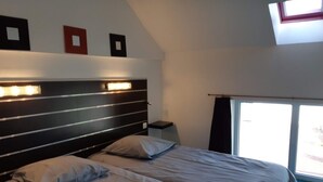 Una camera da letto con un letto, comodini, una finestra e un lucernario.