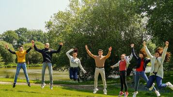 Un grupo de personas saltando en un parque con un estanque y árboles al fondo.