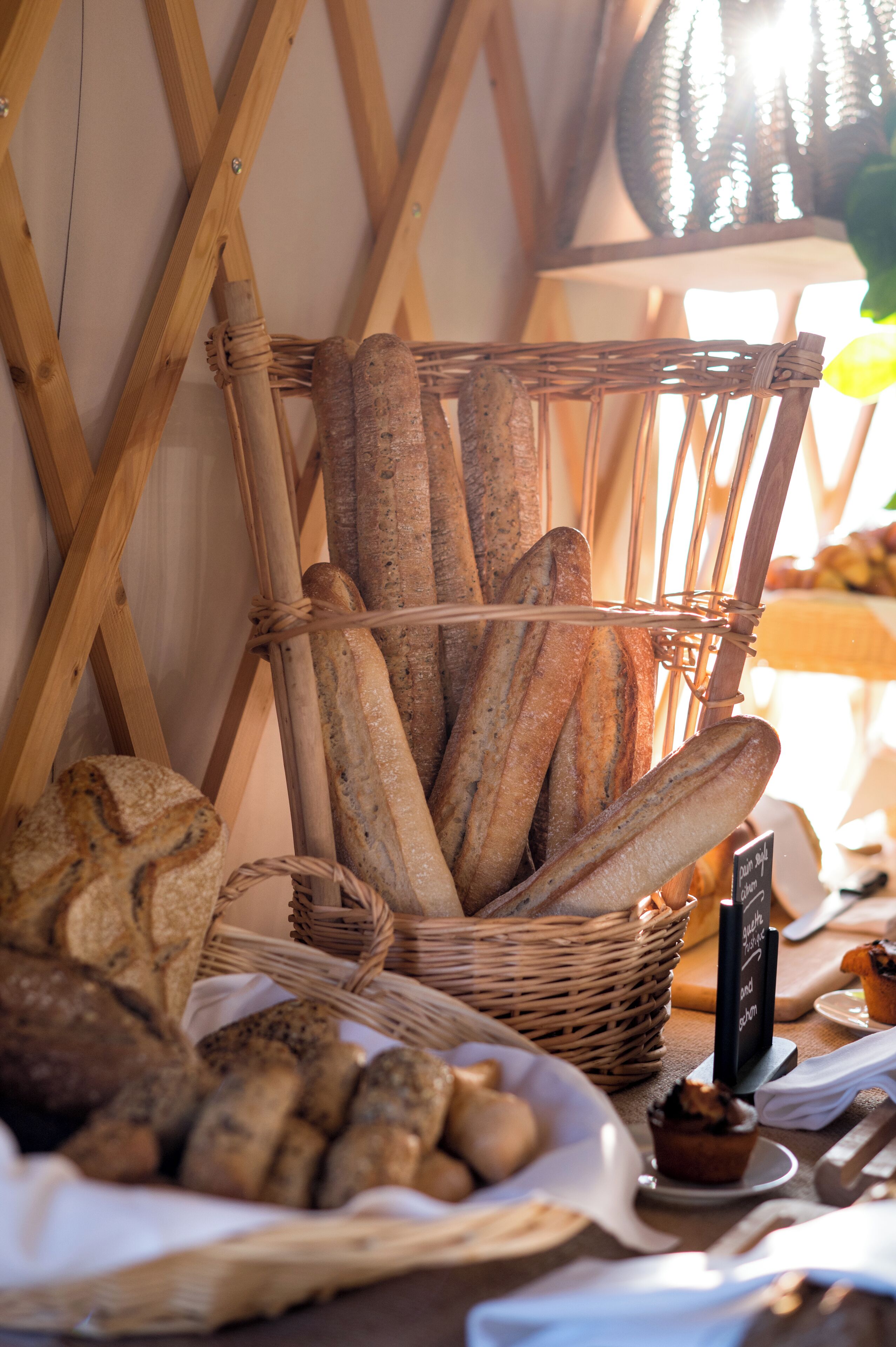 Una cistella de baguettes i pa d'altre tipus damunt d'un taulell amb un cartró negre.