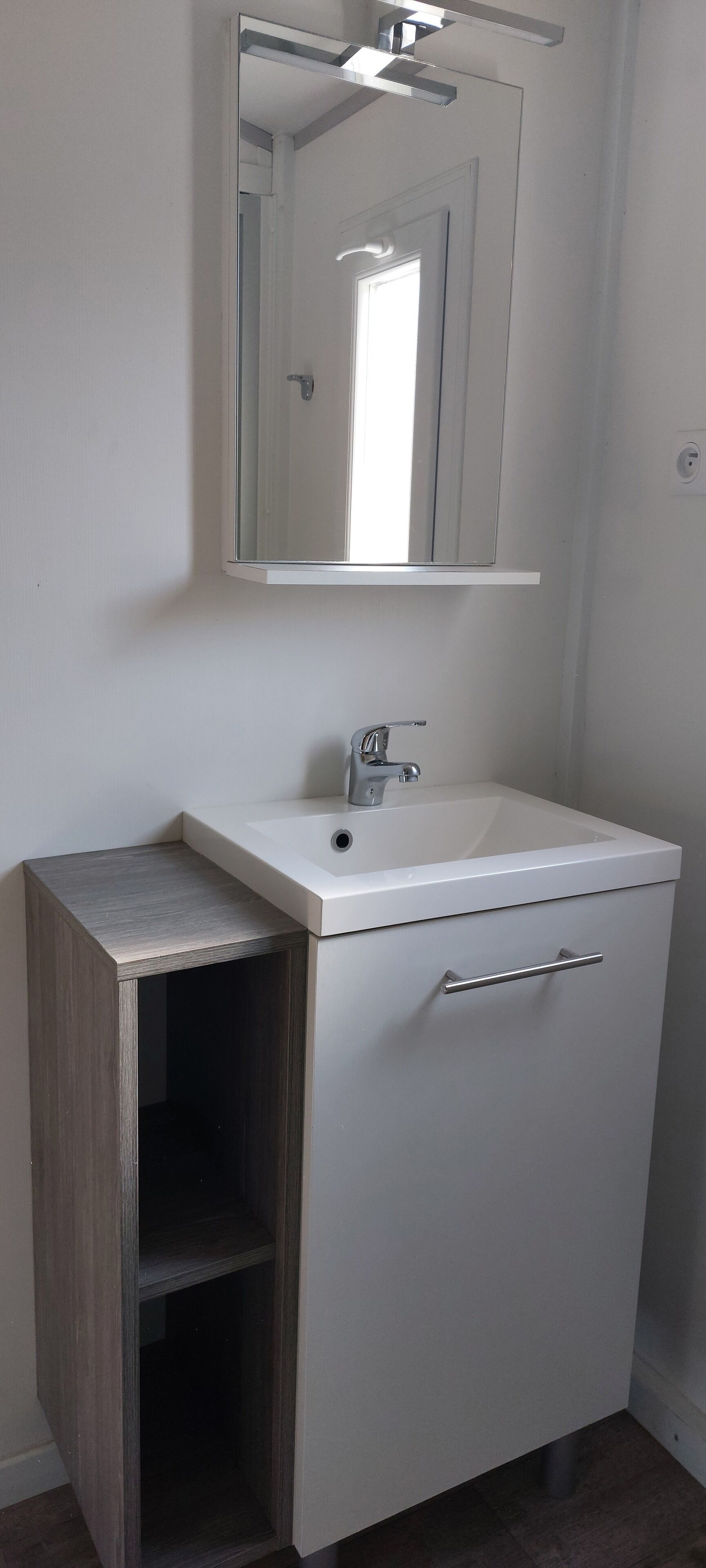 A bathroom with a white sink, a mirror, and a cabinet with a drawer.