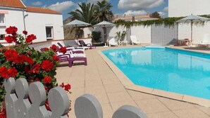 A swimming pool area with lounge chairs, umbrellas, and a white building in the background. - Gîte in the heart of an artists' village - close to the ocean - marsh views (Sallertaine)
