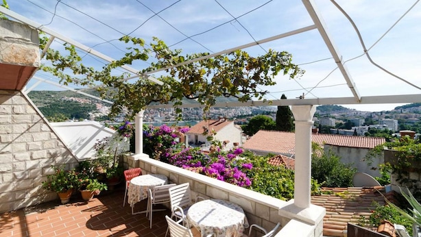 A terrace with a pergola, outdoor seating, and a view of a cityscape. - Guest House Misita (Dubrovnik)