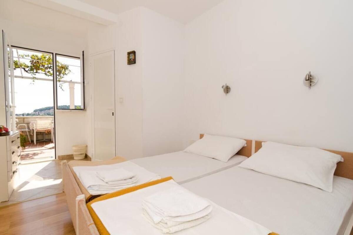 Une chambre avec deux lits, un petit bureau et une fenêtre donnant sur un paysage verdoyant.