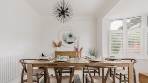 Un comedor con una mesa de madera dispuesta para seis personas, un espejo y un radiador.