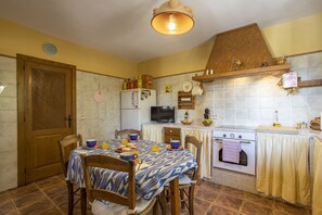 A kitchen with a dining table set for breakfast, a stove, and various kitchen appliances.