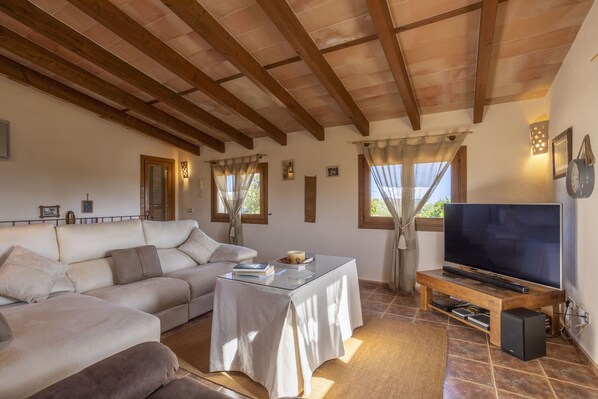 A living room with a sofa, a coffee table, a TV on a wooden stand, and a fireplace. - Rustic property with 3 bedrooms, 2 bathrooms, pool and barbecue. (Inca)