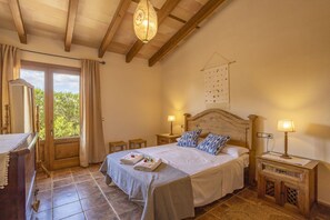 A bedroom with a bed, bedside tables, a wooden desk, and a window with curtains.