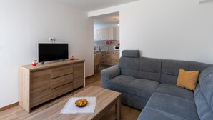 A modern living room with a grey sofa, wooden entertainment unit, and a flat-screen TV. - Apartment Nike (Zupa dubrovacka)