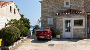 A stone building with a red car parked in front, a door, and a small window. - Apartment Nike (Zupa dubrovacka)