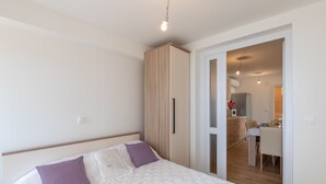 A bedroom with a bed, a wardrobe, and a view into a dining area. - Apartment Nike (Zupa dubrovacka)