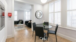 A modern dining area with a round glass table, black chairs, and a large mirror on the wall.